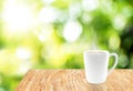 White Coffee cup with hot coffee on wood table at blur green tree bokeh background,Leave space for adding your text Royalty Free Stock Photo