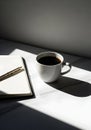 White Coffee Cup and Open Notebook with Pen on Marble Surface with Strong Shadows Royalty Free Stock Photo