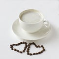 White coffee cup with plate and cofee beans in heart shape isolated on white Royalty Free Stock Photo