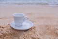 White coffee cup on the sand in the morning day Royalty Free Stock Photo