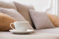 White coffee cup and saucer sits on the arm of the living room sofa