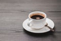 White coffee cup, saucer and spoon on grey wooden background in office table, minimalist flat lay with hot espresso, horizontal Royalty Free Stock Photo