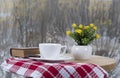 White coffee cup with smoke, brown book and flowers on table in cafe. Snowing outside. Coziness