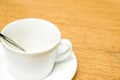 White coffee cup and spoon with saucer on wooden table Royalty Free Stock Photo