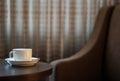 White coffee cup on the table by a sofa couch in hotel room Royalty Free Stock Photo