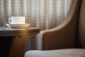 White coffee cup on the table by a sofa couch in hotel room Royalty Free Stock Photo