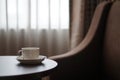 White coffee cup on the table by a sofa couch in hotel room Royalty Free Stock Photo