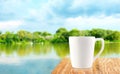 White Coffee cup on wood table at blur tree and lagoon background Royalty Free Stock Photo