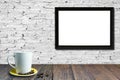 White coffee cup on wooden table, White brick wall background with empty black picture frame for text Royalty Free Stock Photo