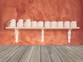 White coffee cups on the wooden shelf with grunge cement wall background,vintage filter effect Royalty Free Stock Photo