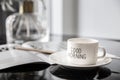 White coffee mug with bouquet of flowers lily of the valley and notes `good morning` on black modern marble table