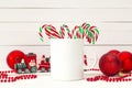 White coffee mug with candy canes and Christmas decorations on w