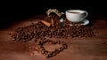 White coffee mug, cinnamon sticks  and coffee beans on the dark wooden background, Heart shape from coffee beans in the foreground Royalty Free Stock Photo