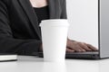 White coffee paper cup mockup with woman working on a computer