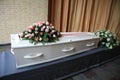 White coffin with pink sympathy flowers