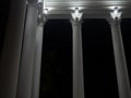 White colonnade in the dark. White columns in the light of spotlights. Element of the architectural ensemble in the city park