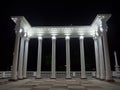 White colonnade in the dark. White columns in the light of spotlights. Element of the architectural ensemble in the city park