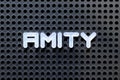 White alphabet with word amity on black pegboard background Royalty Free Stock Photo