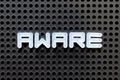 White alphabet with word aware on black pegboard background Royalty Free Stock Photo
