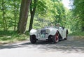 White color Jaguar Suffork SS100 classic car from 1937 driving on a country road