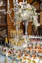 White color wedding table decorated with candelstick. Flowers, candles and glasses with champagne. Closeup.