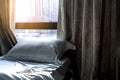 White comfort bed and soft pillow in modern bedroom. Bed near window and curtain at hotel in the morning with sunlight. Linen bed Royalty Free Stock Photo