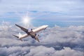 White commercial airplane flying away in to sky high altitude above the white clouds with sunlight Royalty Free Stock Photo