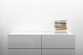 White commode with stack of books in bright minimalism interior