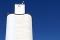 White community co-op cooperative agricultural farm feed grain and corn silo building against a blue sky in rural heartland Royalty Free Stock Photo