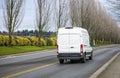 White compact commercial cargo mini van running on the road with trees alley Royalty Free Stock Photo