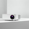 A white, compact multimedia projector is displayed on a minimalist surface. The Royalty Free Stock Photo