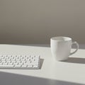 White computer keyboard and a white mug on a light gray surface, bathed in soft sunlight from the right Royalty Free Stock Photo