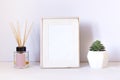 White concept empty frame on the work table with succulent plant and aroma diffuser with wooden sticks. Royalty Free Stock Photo