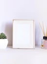 White concept empty frame on the work table with succulent plant and aroma diffuser with wooden sticks. Royalty Free Stock Photo