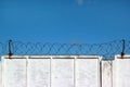 White concrete fence with barbed wire against a blue sky Royalty Free Stock Photo