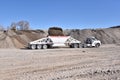 White construction truck and trailer being loaded with gravel with loader in gravel pit Royalty Free Stock Photo