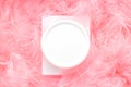 White container cream jar and pink feathers top view composition. Creative minimal beauty flat lay compositionon Royalty Free Stock Photo