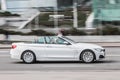 White convertible car BMW F33 4-series at the city street in motion. Side view of fast moving BMW cabrio Royalty Free Stock Photo