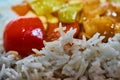 White cooked rice, with fuzzy red, yellow and green vegetables in the background Royalty Free Stock Photo