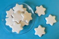 White cookies in the shape of stars on the transparent saucer and on blue background