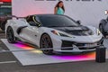 A white Corvette, showcased on an elevated platform at a car event, under vibrant LED lighting Sleek design with angular Royalty Free Stock Photo