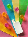 White cosmetic bottle and colorful transparent cubes on bright background