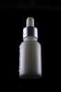 White cosmetic bottle with an eyedropper is isolated on a black background