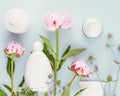 White cosmetic bottles, tube, jar with cream and pink peonies