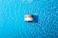 White cosmetic jar on the blue water surface. Blank label for branding mock-up. Summer water pool fresh concept. Flat lay, top