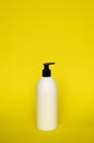 White cosmetic plastic bottle with black pump dispenser on yellow background. Liquid container for gel, lotion, cream Royalty Free Stock Photo