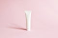 White cosmetic products tube. Blank plastic container for cream, lotion, toothpaste, nourishing or moisturizing mask on a pink bac Royalty Free Stock Photo