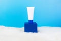 White cosmetic products tube on stand on blue background. Blank plastic container for cream, lotion, toothpaste Royalty Free Stock Photo