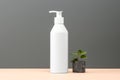 White cosmetic shampoo dispenser bottle mockup and stone with plant on gray background. Royalty Free Stock Photo