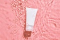 White cosmetic tube on the pink water surface. Blank label for branding mockup. Flat lay, top view. beauty spa medical skincare